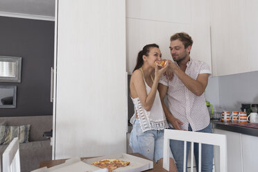 Young couple eating pizza in kitchen - WESTF23261