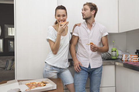 Junges Paar isst Pizza in der Küche, lizenzfreies Stockfoto