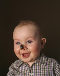 Porträt eines aufgeregten kleinen Jungen mit einer Spielzeugfliege auf der Nase - FSF00913