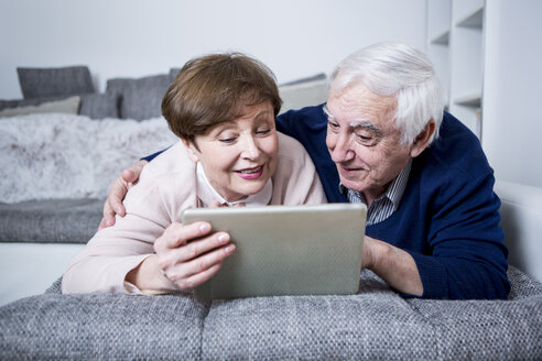 Älteres Ehepaar auf der Couch liegend mit digitalem Tablet - WESTF23304