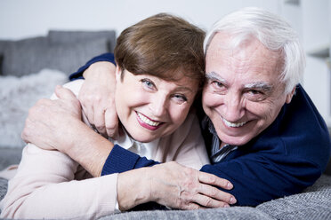 Senior couple lying on couch, hugging - WESTF23305