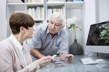 Senior couple with bills and calculator checking their expenses - WESTF23315