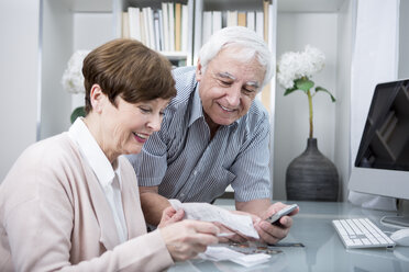 Senior couple with bills and calculator checking their expenses - WESTF23316