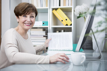 Ältere Frau arbeitet am Computer mit einer Tasse Kaffee - WESTF23323