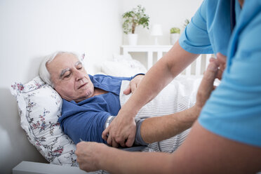 Gynäkologin misst den Blutdruck eines im Bett liegenden Patienten - WESTF23352