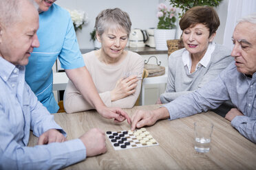 Nurse helping with a games evening for elderly people - WESTF23369