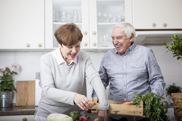 Älteres Ehepaar steht in der Küche und packt frisches Gemüse aus - WESTF23380