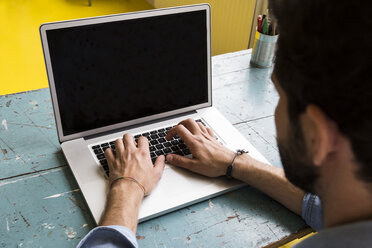 Mann sitzt am Schreibtisch und arbeitet mit seinem Laptop - ABZF02056