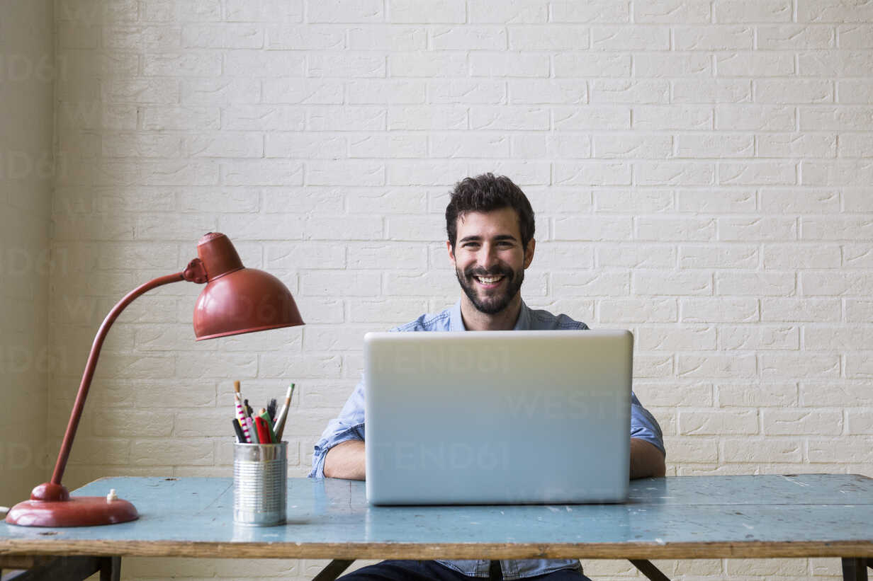 https://us.images.westend61.de/0000789595pw/portrait-of-happy-young-man-sitting-at-desk-working-with-laptop-ABZF02068.jpg