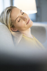 Porträt einer blonden Frau mit geschlossenen Augen, die sich auf der Couch entspannt - JOSF01066