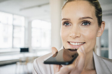 Porträt einer lächelnden Geschäftsfrau, die ein Mobiltelefon benutzt - JOSF01071