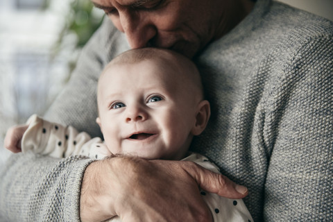 Reifer Vater küsst lachendes Baby auf den Kopf, lizenzfreies Stockfoto