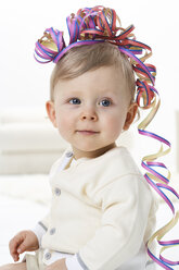 Porträt eines lächelnden Kleinkindes mit Luftschlange auf dem Kopf - FSF00933