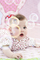 Porträt eines staunenden kleinen Mädchens, das Seifenblasen beobachtet - FSF00939