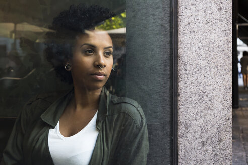 Porträt einer jungen Frau, die aus dem Fenster eines Cafés schaut - ABZF02084