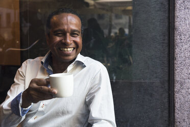Porträt eines lachenden Mannes in einem Café mit einer Tasse Kaffee - ABZF02086