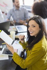 Porträt einer lächelnden Geschäftsfrau während einer Sitzung im Büro - GIOF02640