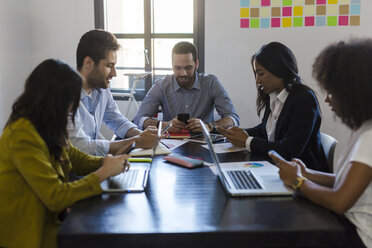 Business people using cell phones during a meeting in office - GIOF02650