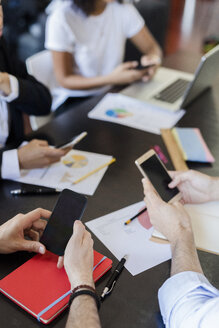 Geschäftsleute benutzen Mobiltelefone während einer Besprechung im Büro - GIOF02653