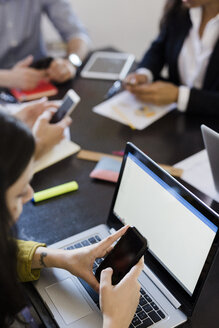 Geschäftsleute benutzen Mobiltelefone während einer Besprechung im Büro - GIOF02654