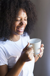 Lachende Frau mit einer Tasse Kaffee in der Hand - GIOF02672