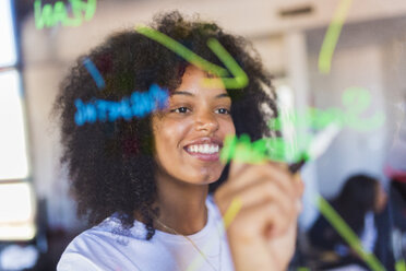 Businesswoman writing on glass wall - GIOF02686