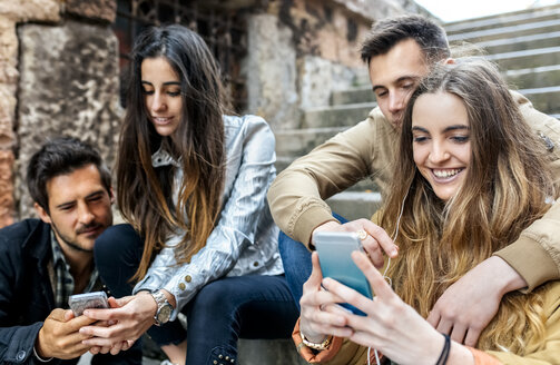 Gruppe von Freunden, die mit dem Smartphone Nachrichten versenden - MGOF03407