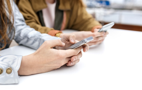 Nahaufnahme von zwei Frauen, die mit ihren Smartphones Nachrichten versenden, lizenzfreies Stockfoto