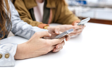 Close-up of two women sending messages with their smartphones - MGOF03419