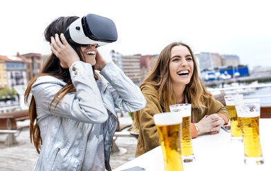 Two young women having fun with VR glasses in the city - MGOF03422