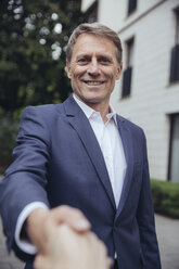 Portrait of smiling mature businessman shaking hands outdoors - MFF03611