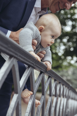 Vater hält sein Baby, um über einen Zaun zu schauen, lizenzfreies Stockfoto