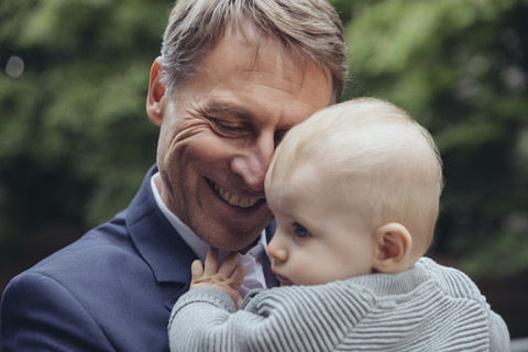 Happy mature businessman holding baby boy outdoors stock photo