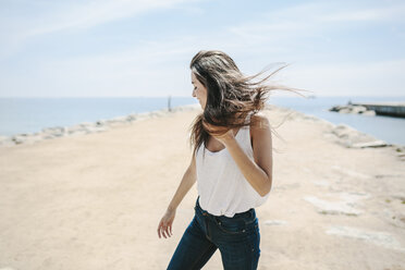 Young woman standing on the beach, enjoying wind - GIOF02729
