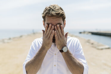 Mittlerer erwachsener Mann am Strand, der die Augen bedeckt - GIOF02732