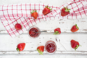 Two glasses of homemade strawberry jam, kitchen towel and strawberries on white wood - LVF06152