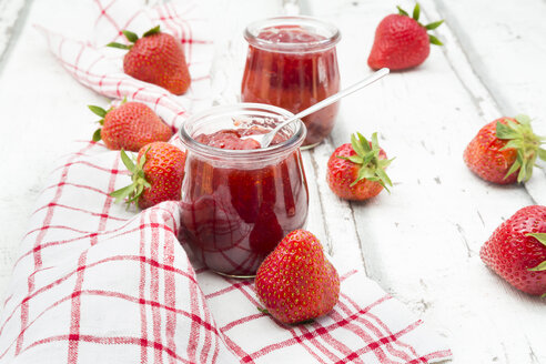 Glas mit selbstgemachter Erdbeermarmelade, Küchentuch und Erdbeeren auf weißem Holz - LVF06154