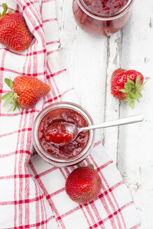 Glas mit selbstgemachter Erdbeermarmelade, Küchentuch und Erdbeeren auf weißem Holz - LVF06155