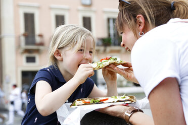 Italien, Mutter und kleine Tochter essen zusammen Pizza - FKF02337