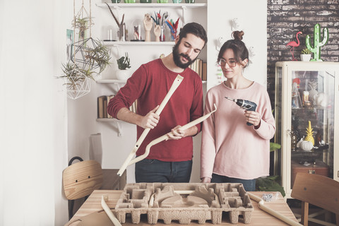 Junges Paar beim Zusammenbau eines Hockers zu Hause, lizenzfreies Stockfoto