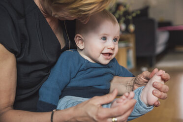 Frau spielt mit den Füßen eines kleinen Jungen zu Hause - MFF03627