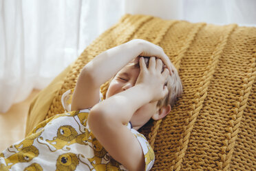 Kleiner Junge liegt auf einem Kissen und bedeckt sein Gesicht mit seinen Händen - MFF03633