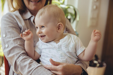 Happy baby boy sitting on lap of his grandmother - MFF03636