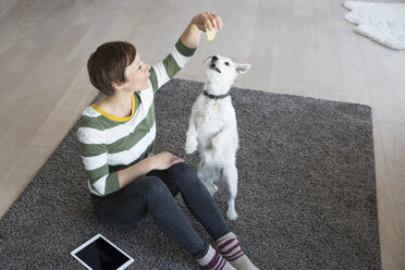 Woman sitting on the floor in the living room with her dog - RBF05669