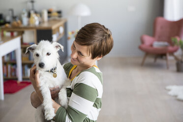 Frau hält Hund auf ihren Armen zu Hause - RBF05671