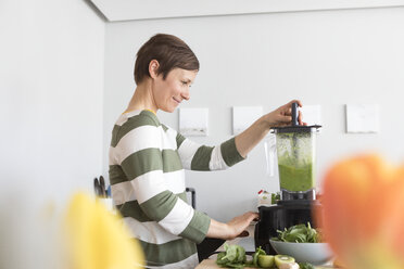 Smiling woman preparing green smoothie in the kitchen - RBF05679