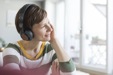 Smiling woman listeningmusic with headphones at home - RBF05699