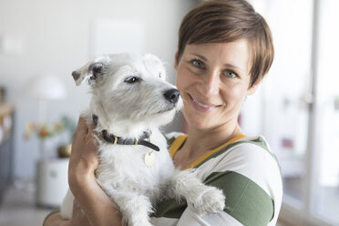 Portrait of smiling woman holding dog on her amrs - RBF05702