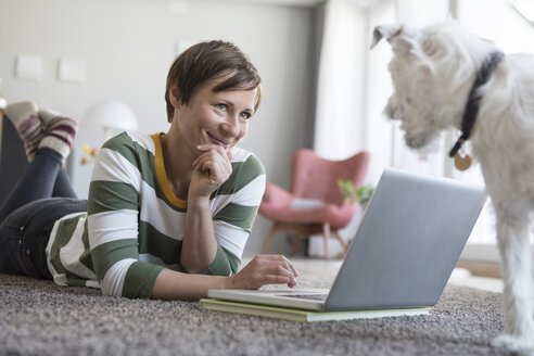 Lächelnde Frau auf dem Boden liegend mit Laptop - RBF05706