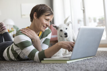 Lächelnde Frau auf dem Boden liegend mit Laptop - RBF05707